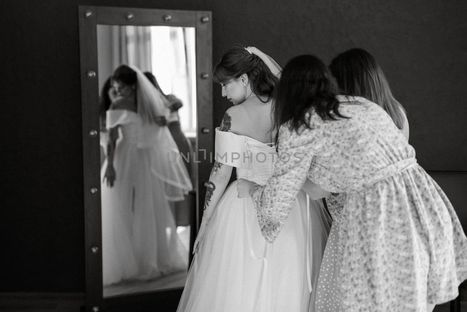 preparations for the bride with the dressing of the wedding dress in the studio