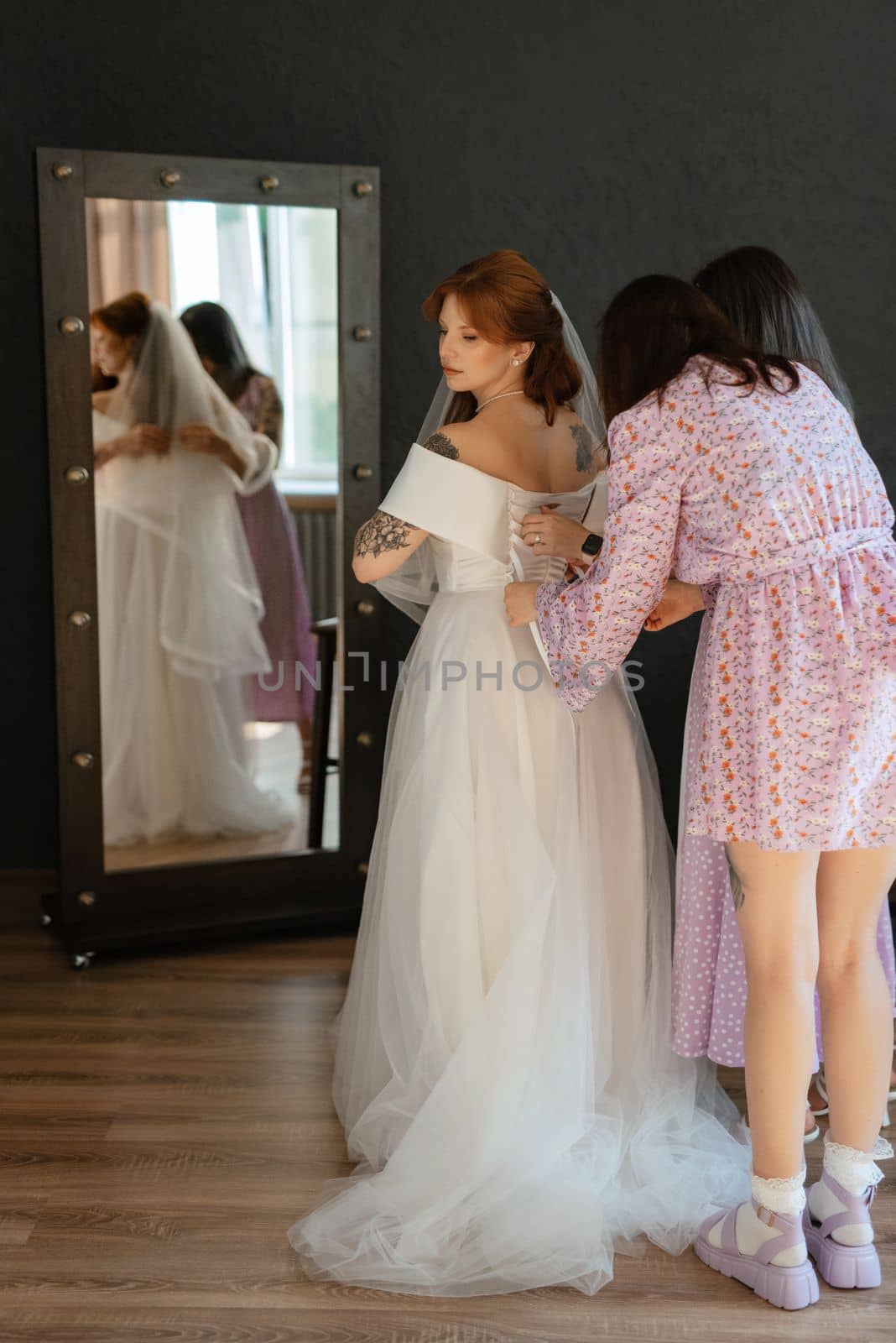 preparations for the bride with the dressing of the wedding dress in the studio