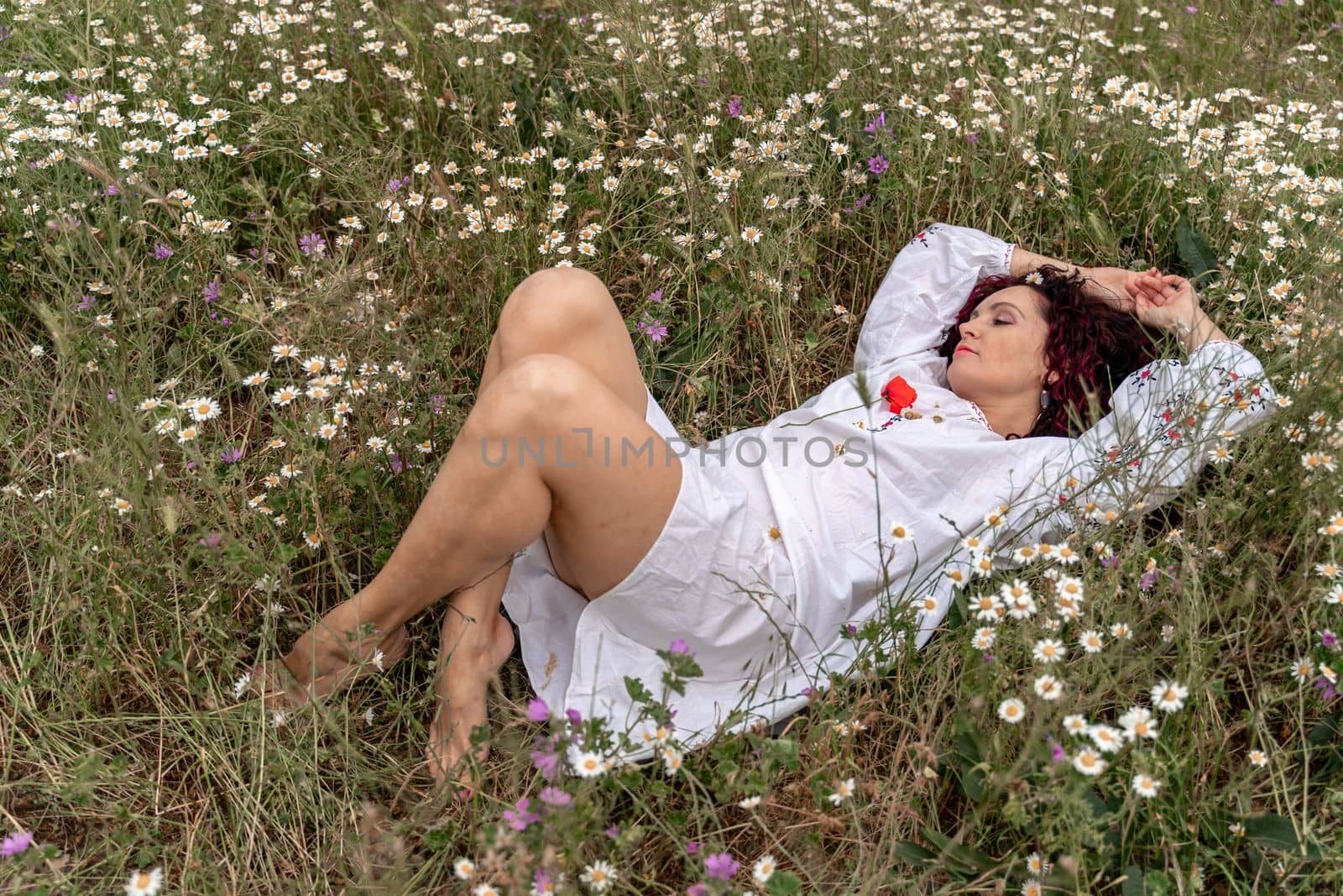 A beautiful woman lies on her back in a field and lifts up her beautiful legs. Good morning.