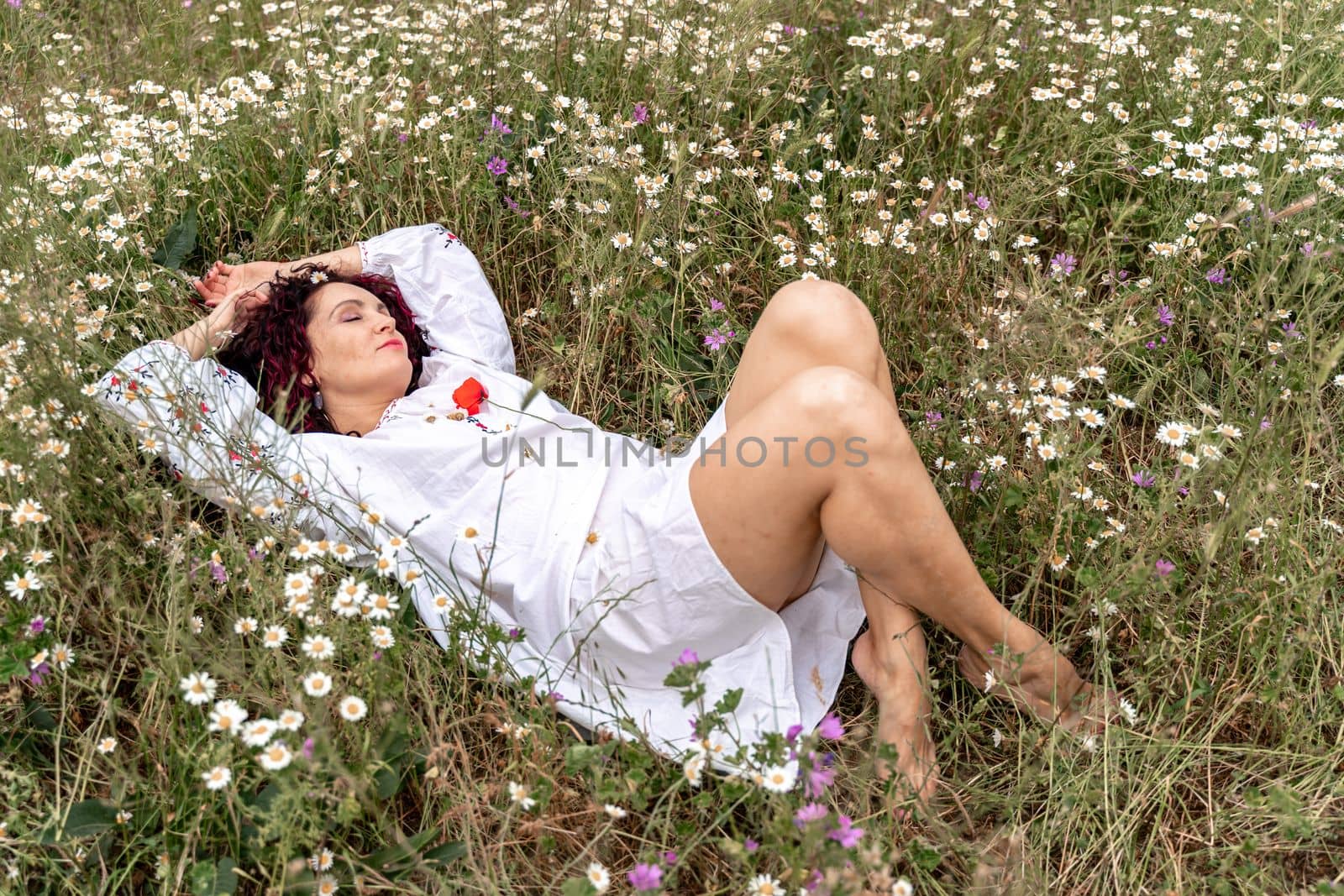 A beautiful woman lies on her back in a field and lifts up her beautiful legs. Good morning.