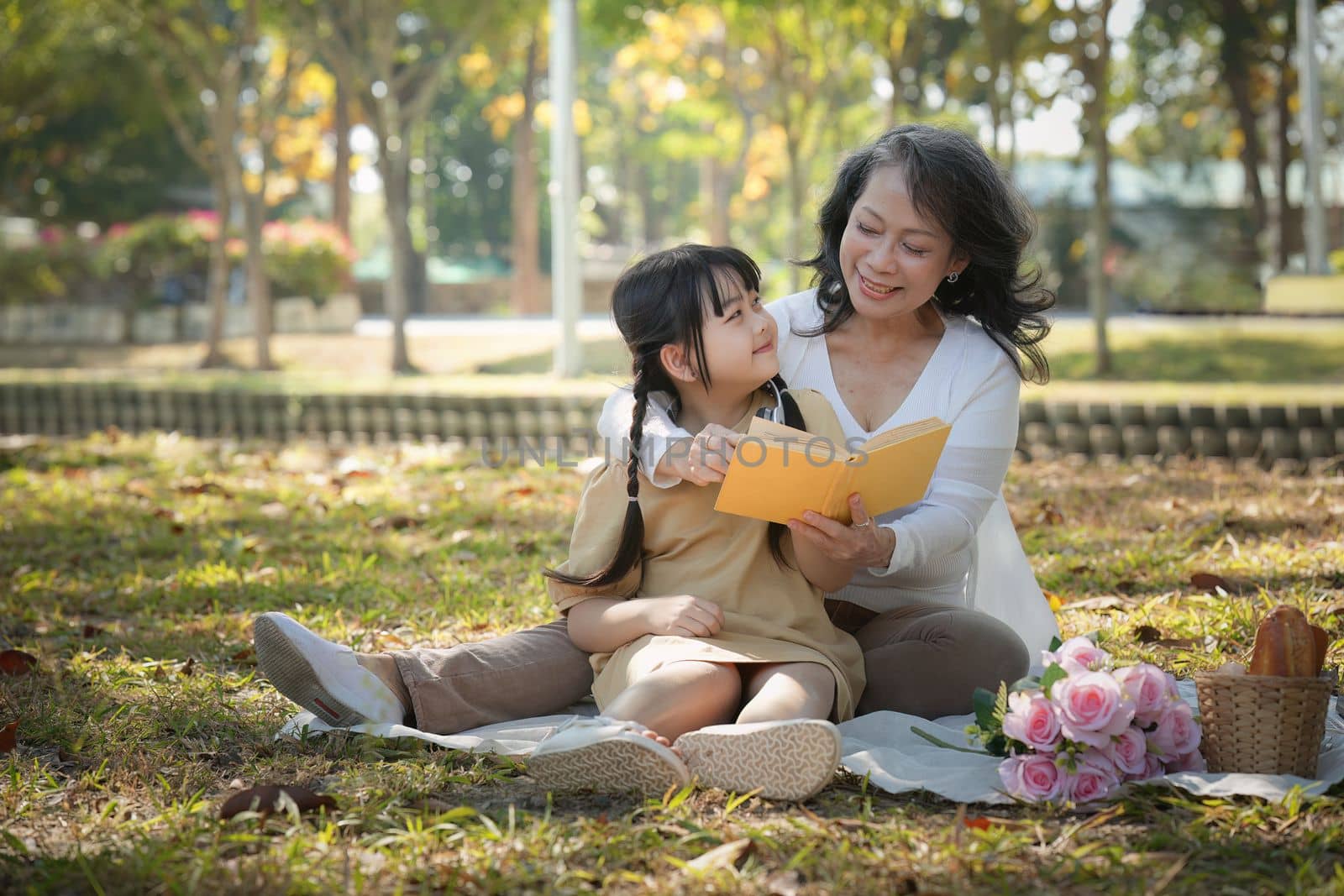 Asian Grandmother and Granddaughter having activity together outdoor park. Hobbies and leisure, lifestyle, family life, happiness moment concept by itchaznong