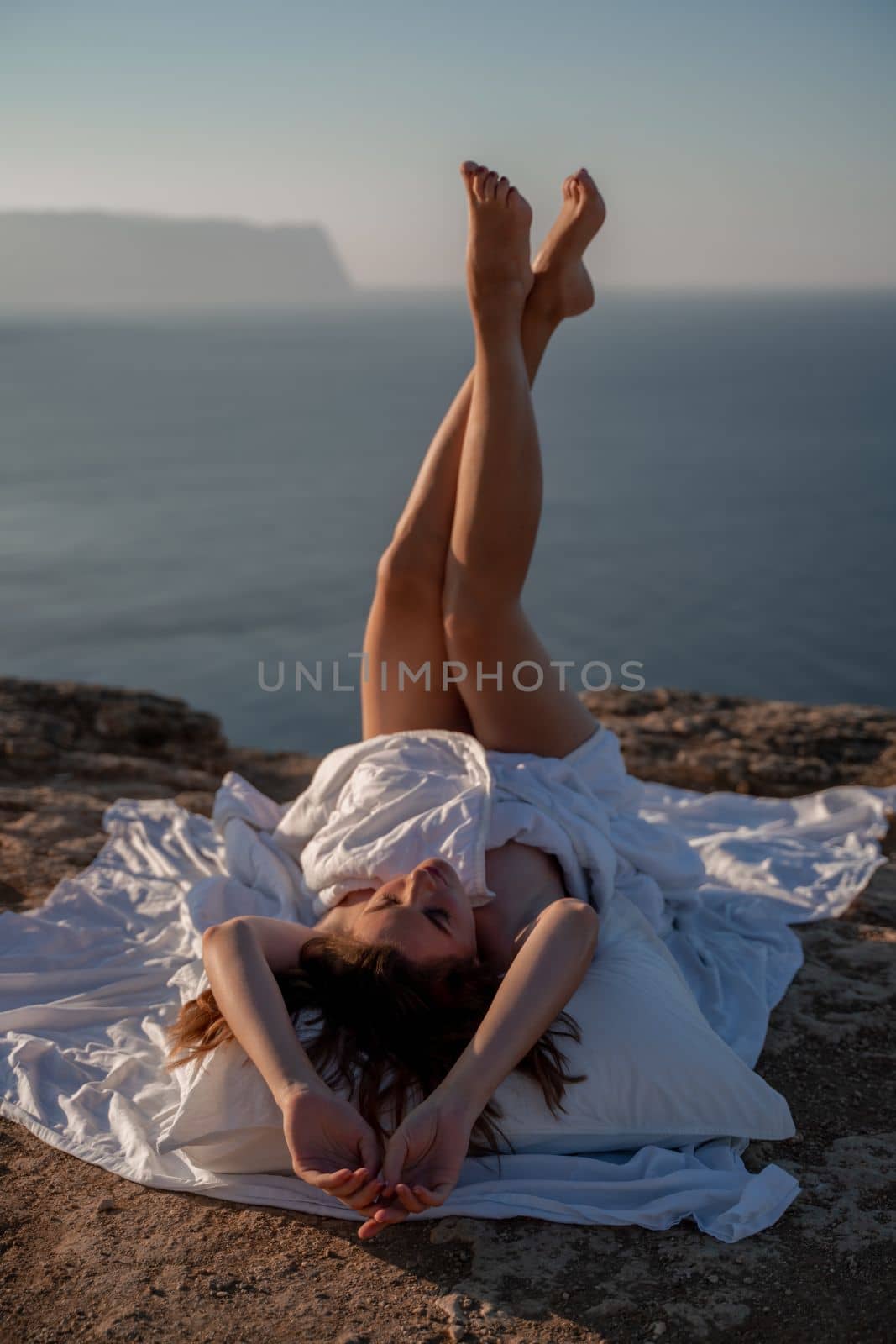 Woman wake up in bed wuth duvet and pillow over nature sea background outdoors. Back view. Good morning. Freedom concept. by Matiunina