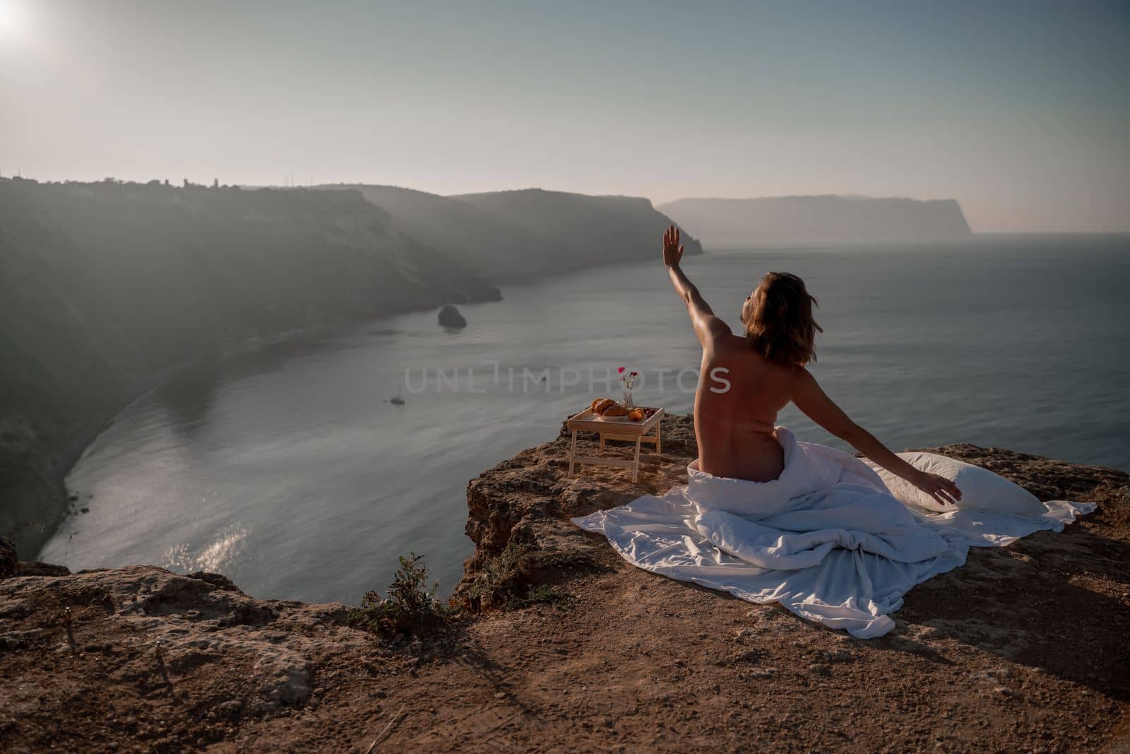 Woman wake up in bed wuth duvet and pillow over nature sea background outdoors. Back view. Good morning. Freedom concept. by Matiunina