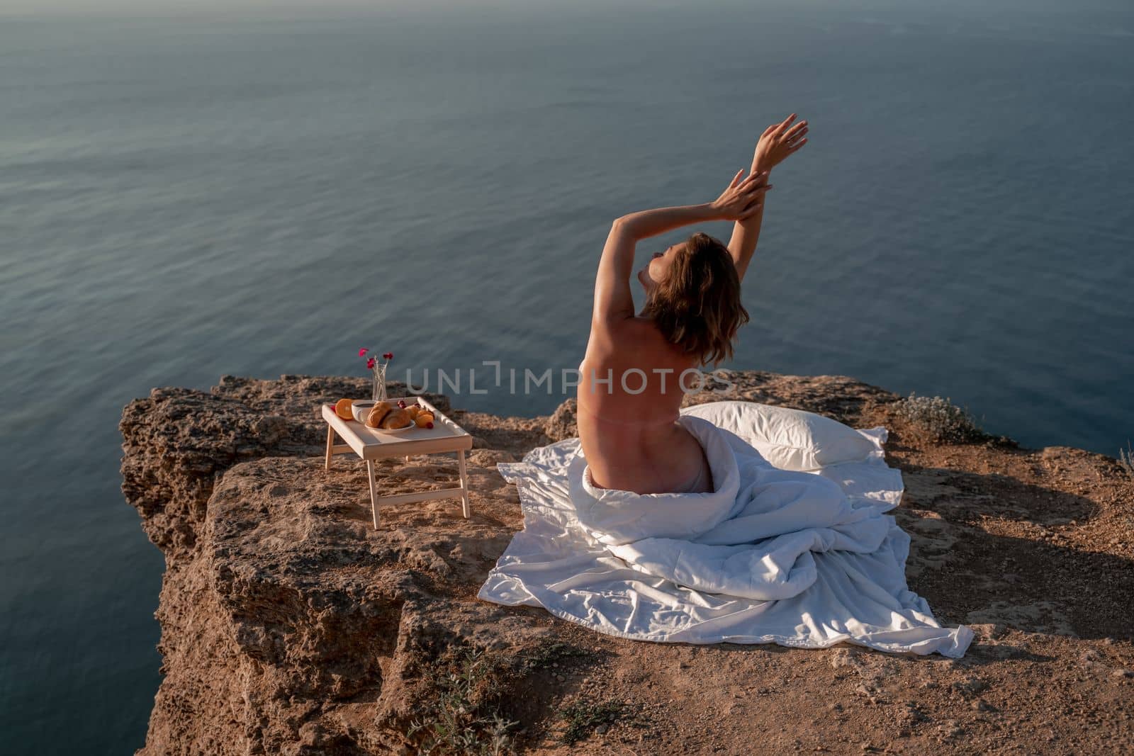 Woman wake up in bed wuth duvet and pillow over nature sea background outdoors. Back view. Good morning. Freedom concept. by Matiunina