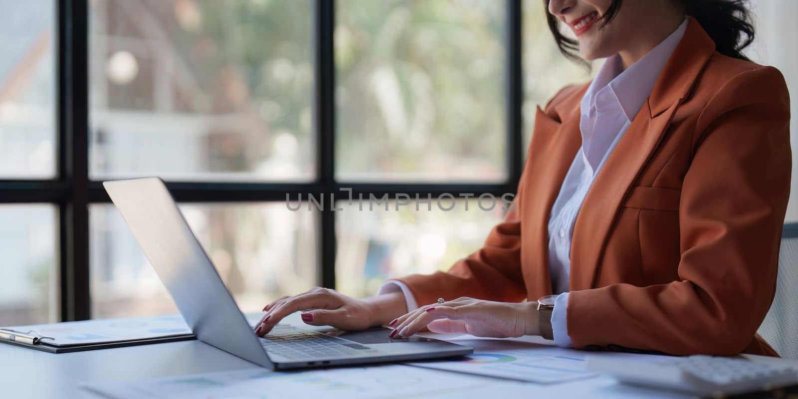 Asian businesswoman or accountant in closeup examining financial report on laptop during work.