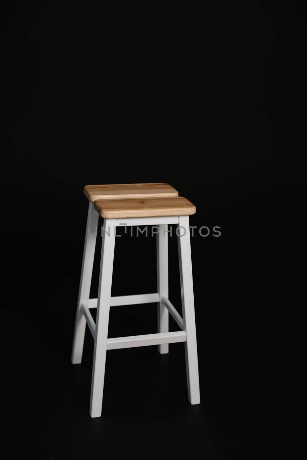 minimalistic wooden chair against black background. Concept modern interior and design furniture in room. High stool in loft style. Retro Bar chair. Vintage wooden metal chair