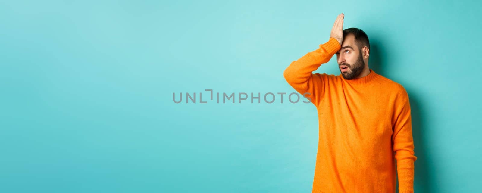 Annoyed man roll eyes and making facepalm, standing over turquoise background by Benzoix