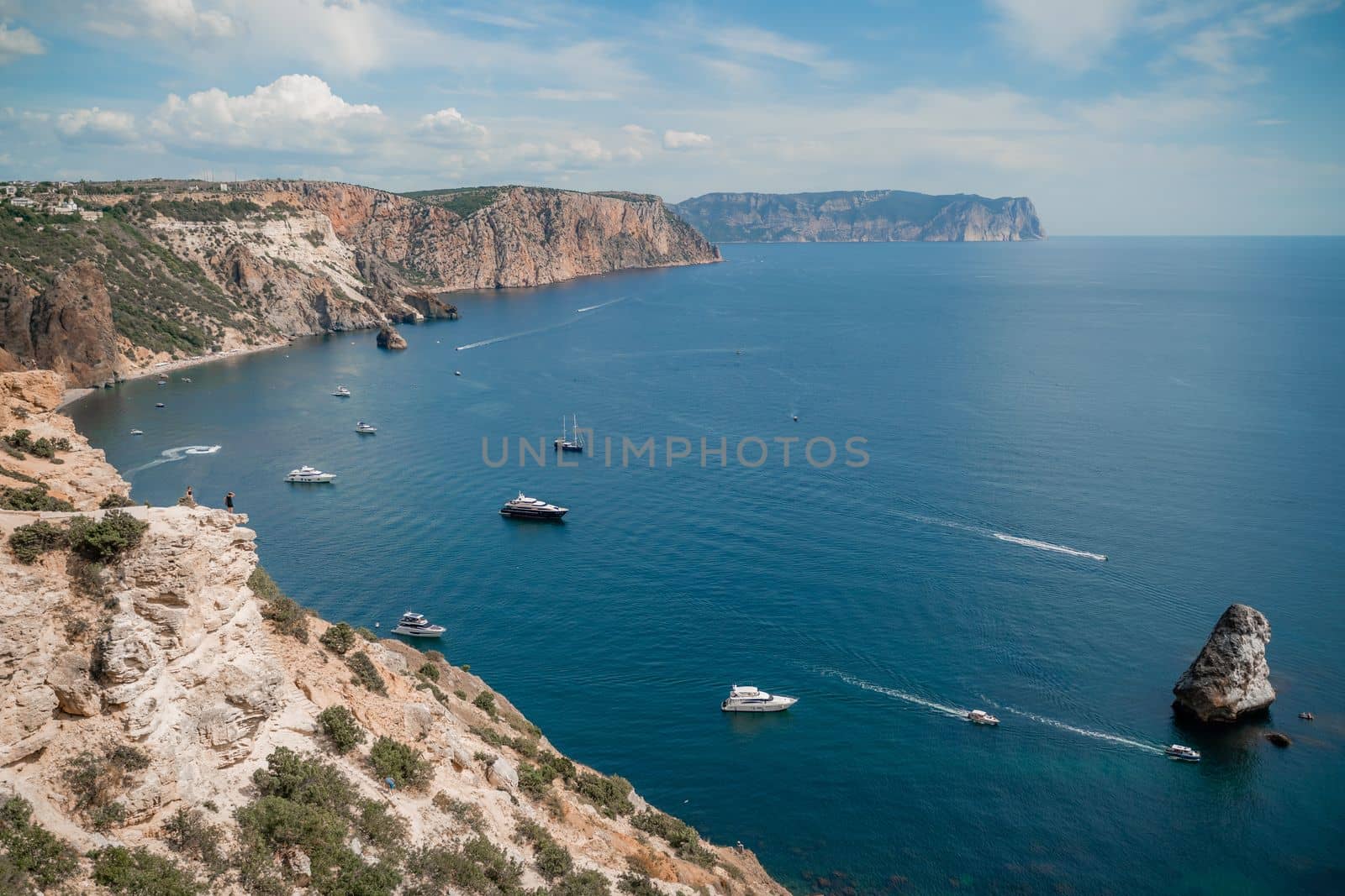 Two rocks stick out of the water in the middle of the turquoise sea. Scenic ocean view. Speed boat sails on the sea. High quality photo by Matiunina