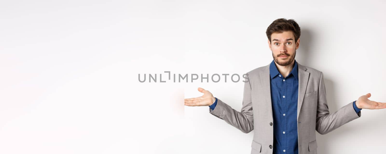 Dont know. Confused businessman spread hands sideways and look clueless, cant help, have no idea, standing on white background in suit.