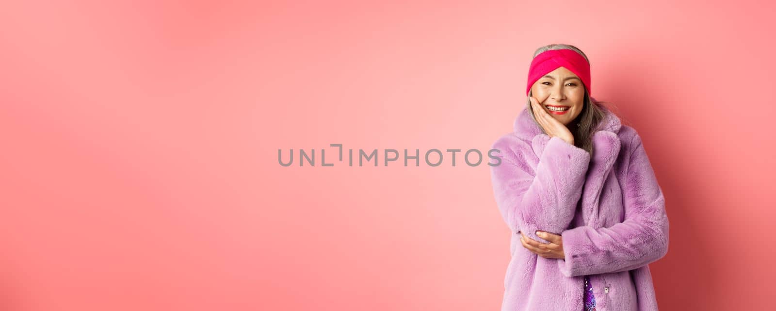 Fashion and shopping. Beautiful and romantic asian mature woman looking caring and heartfelt at camera, smiling happy, standing over pink background.