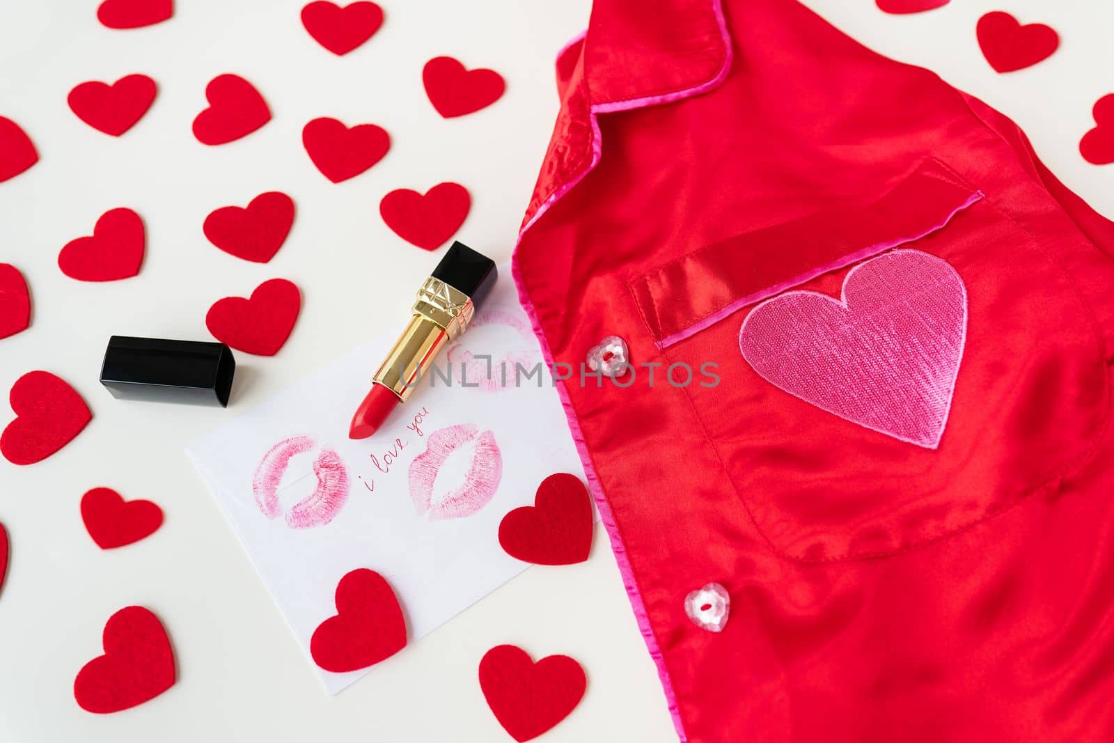 The inscription I love you on a white envelope with a print of lips in red lipstick on a background of small red hearts and a red shirt. Valentine's day concept. by sfinks