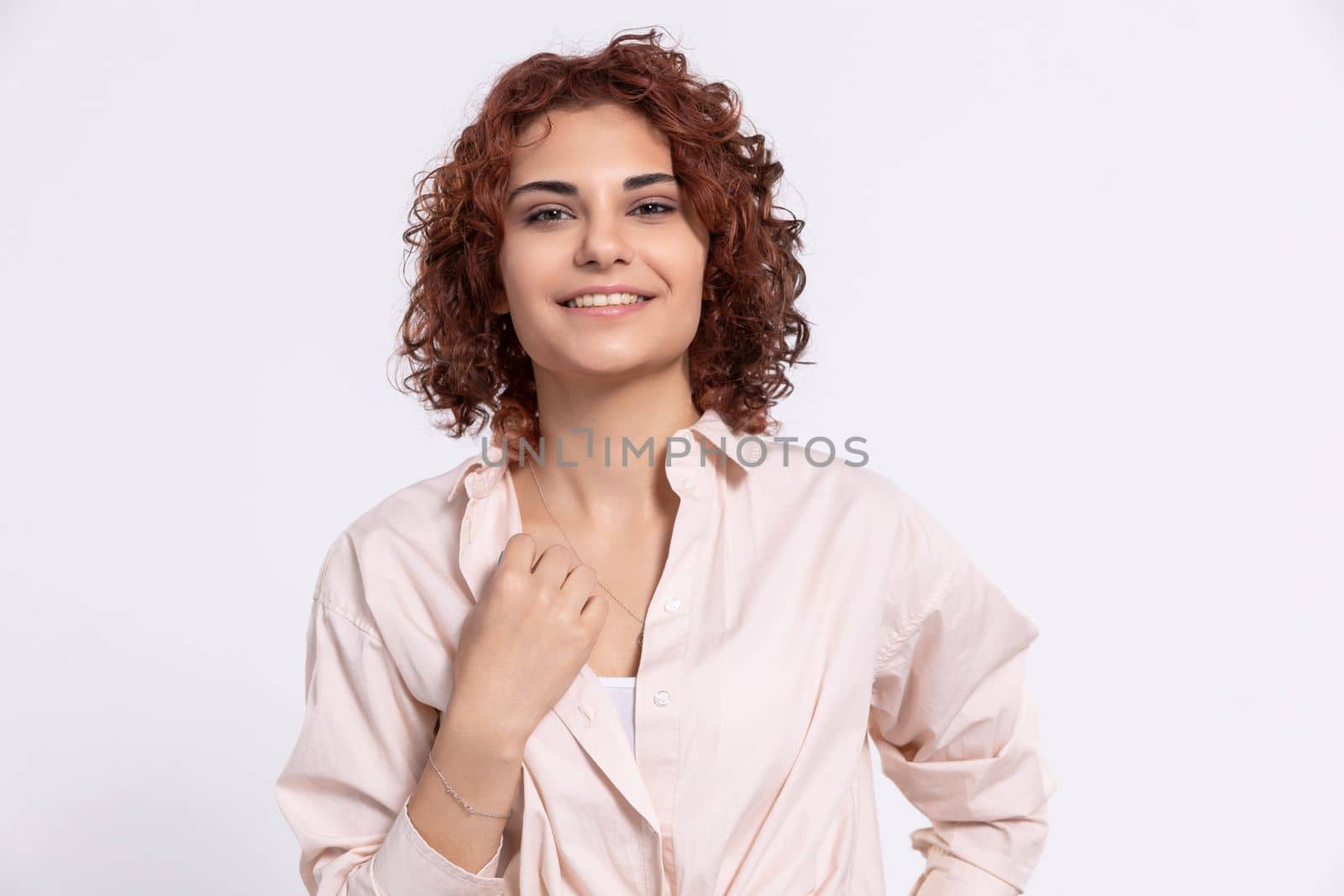 Sincere smile of a young European woman. Attractive girl with short chestnut-colored hair. Naturally curly hair.