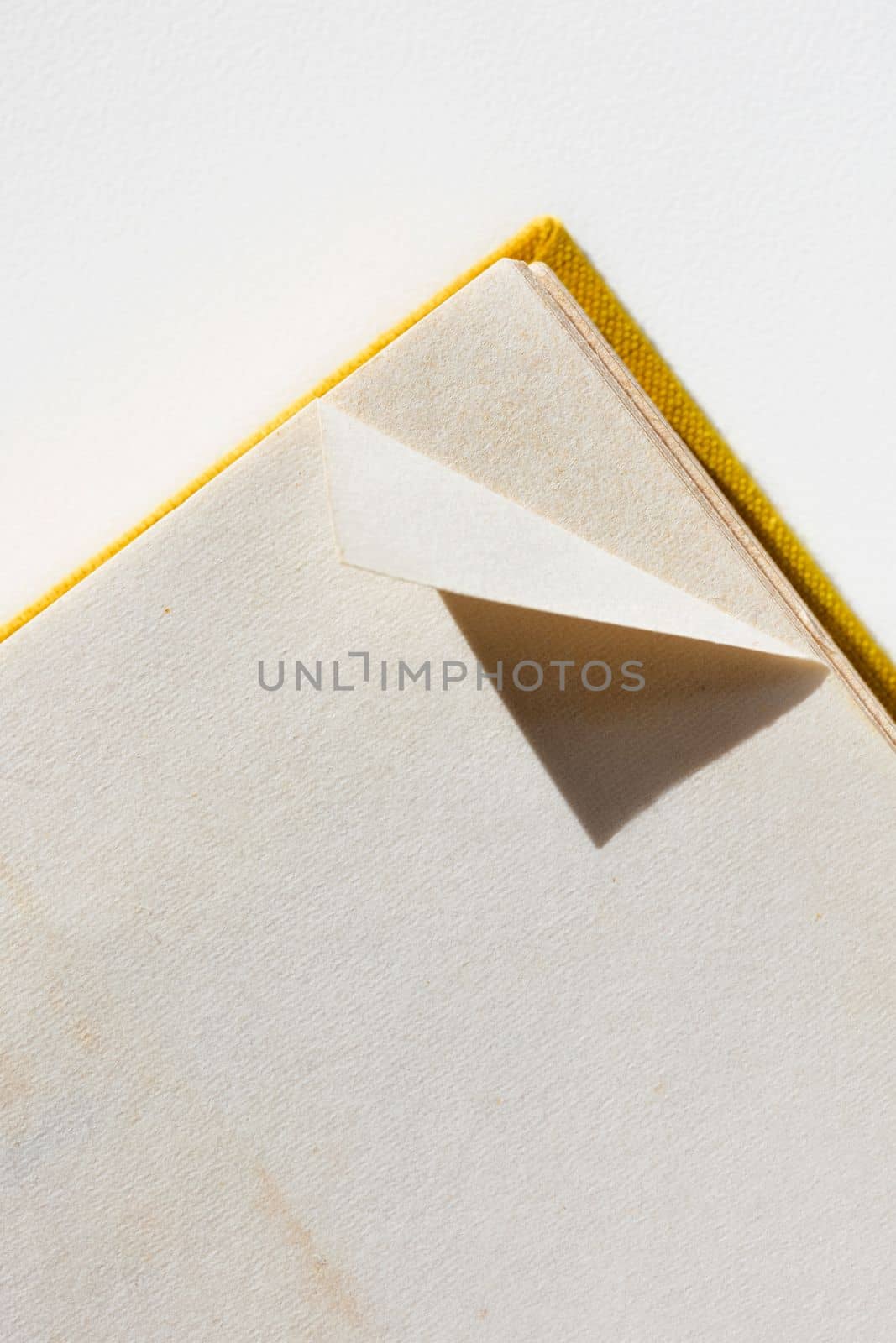 A dog-eared page in opened book on white table 
