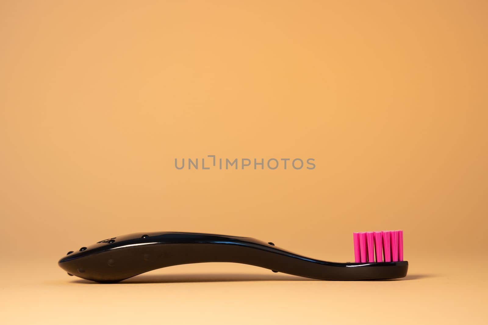 Neon pink plastic baby tooth brush on natural background. Dental and healthcare concept