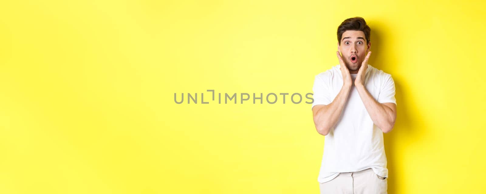 Image of handsome man looking surprised, gasping and saying wow, looking at promo offer amazed, standing over yellow background by Benzoix