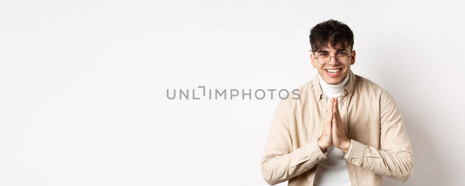 Handsome caucasian man say thank you, bowing with namaste gesture, looking grateful and smiling at camera, standing on white background.