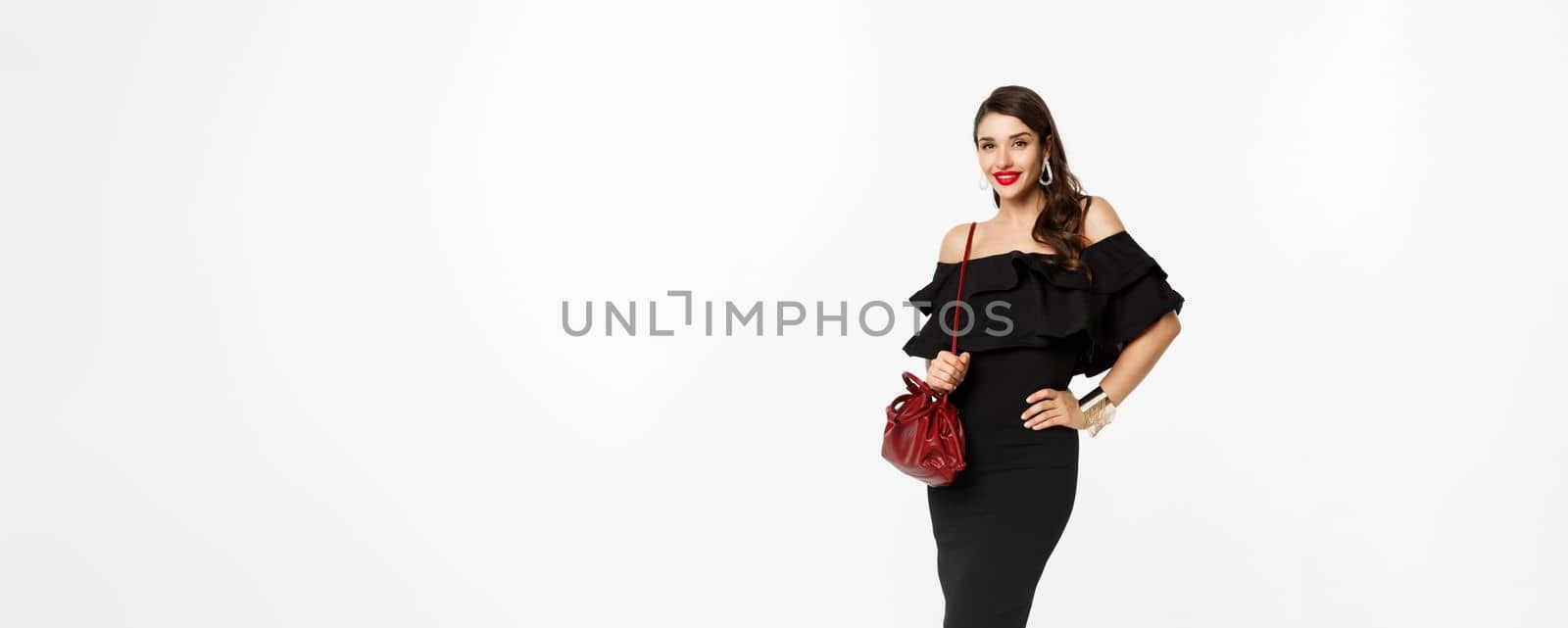Beauty and fashion concept. Full length of elegant young woman going shopping in black dress, heels and purse, looking confident, standing over white background by Benzoix
