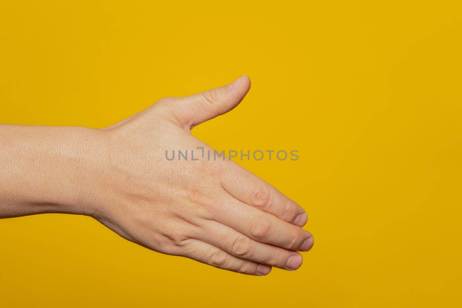 Man stretching out his hand to handshake isolated on a yellow background. Man's hand ready for handshake. Alpha