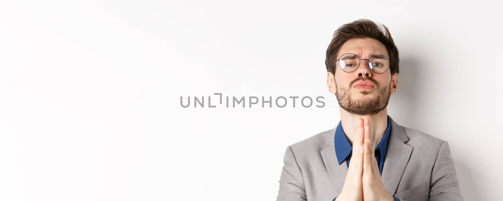 Clingy guy in glasses asking for last favour, begging for help and looking sad cute eyes, standing on white background.