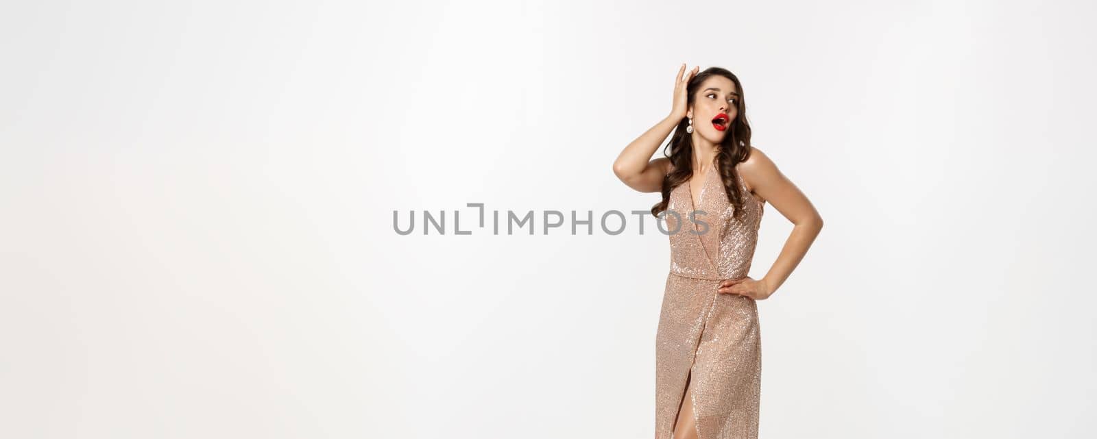 Party and celebration concept. Full-length of perfect woman in elegant dress laughing, standing near Christmas presents, white background. Copy space