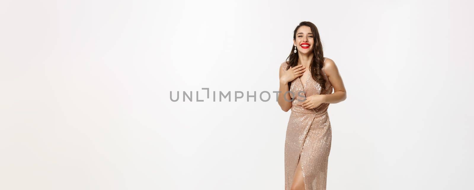 Party and celebration concept. Full-length of beautiful woman in elegant dress standing near Christmas gifts, laughing happy, standing over white background by Benzoix