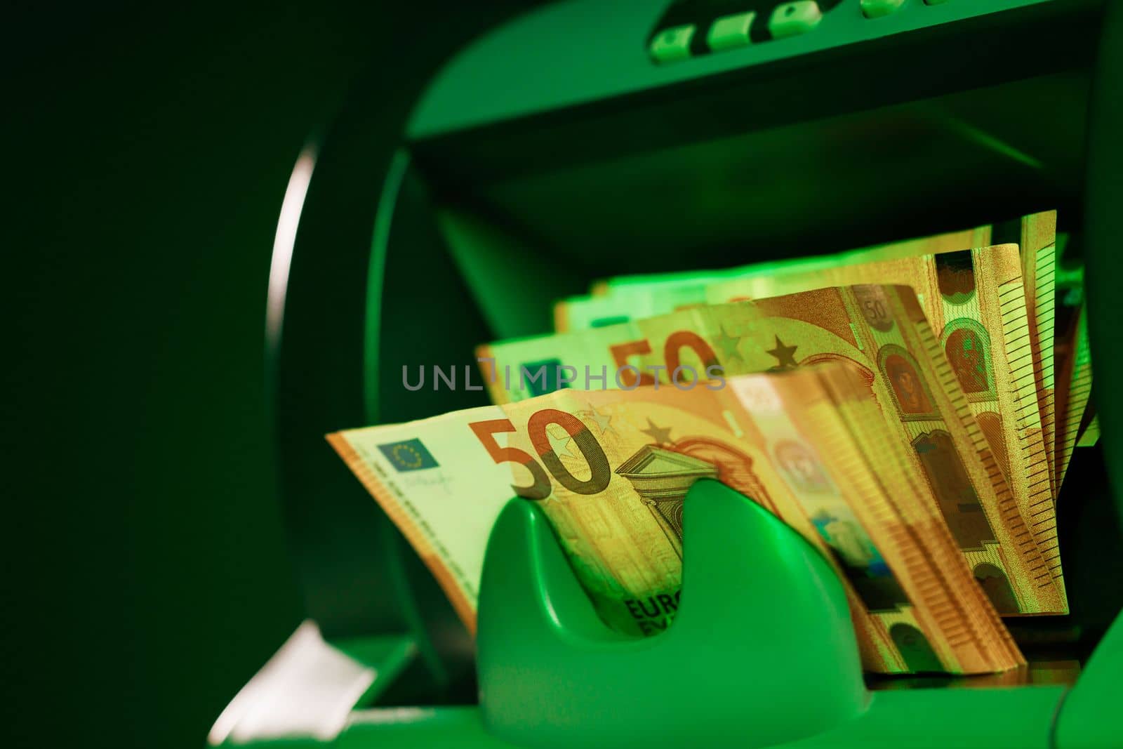 Electronic money counter machine is counting the euro banknotes. Automatic money counting in the machine. Close up of euro banknotes while being counted by uflypro