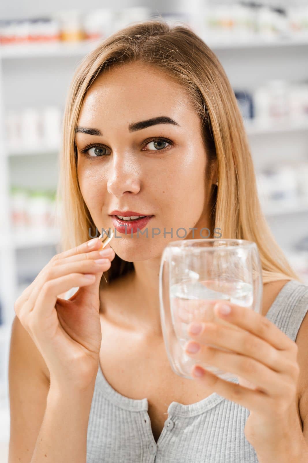 Girl with Omega-3 capsule and cup of water is ready to take a BADS capsule of Omega-3. Biologically active dietary supplements. Taking vitamin D for building and maintaining healthy bones. by Rabizo