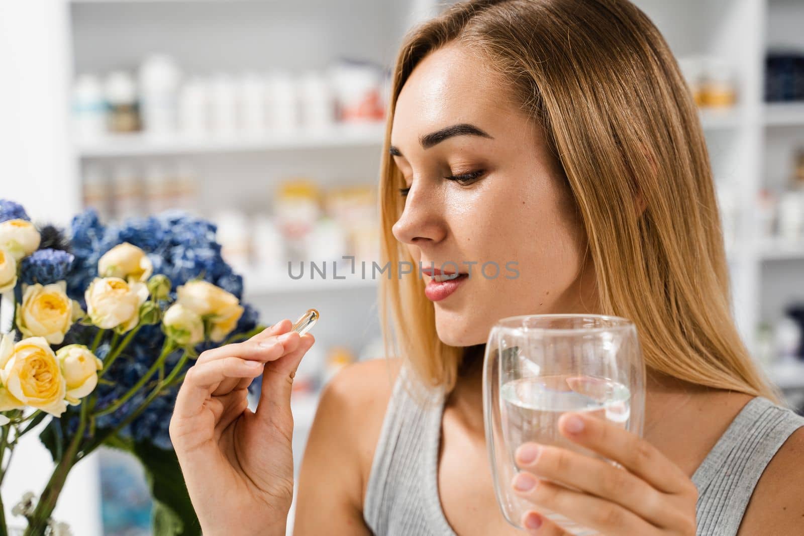 Girl with Omega-3 capsule and cup of water is ready to take a BADS capsule of Omega-3. Biologically active dietary supplements. Taking vitamin D for building and maintaining healthy bones