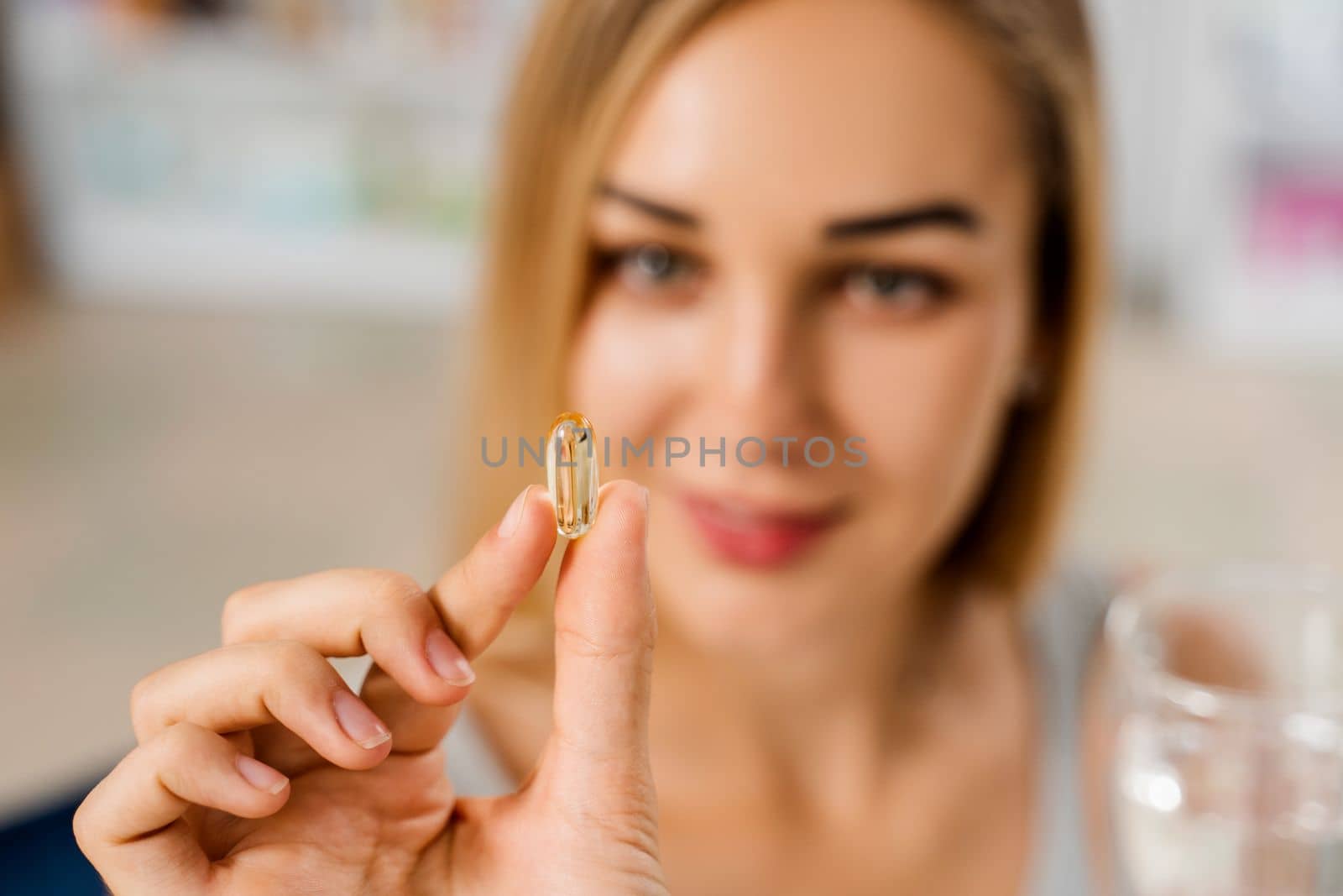 Girl with Omega 3 pill of fish fat oil in hands. BADS capsule of biologically active dietary supplements. Vitamin D for building and maintaining healthy bones. by Rabizo