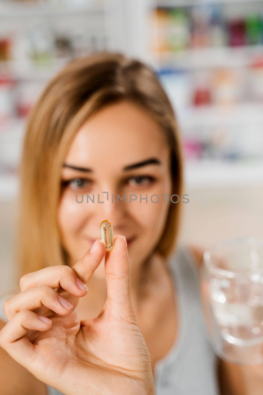 Girl with Omega 3 pill of fish fat oil in hands. BADS capsule of biologically active dietary supplements. Vitamin D for building and maintaining healthy bones. by Rabizo