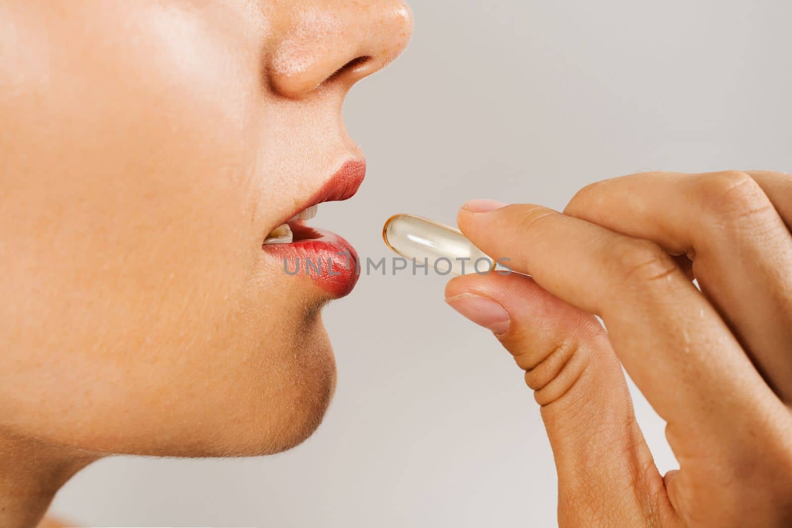 Girl is taking BADS capsule of Omega-3 biologically active dietary supplements close-up. Vitamin D for building and maintaining healthy bones