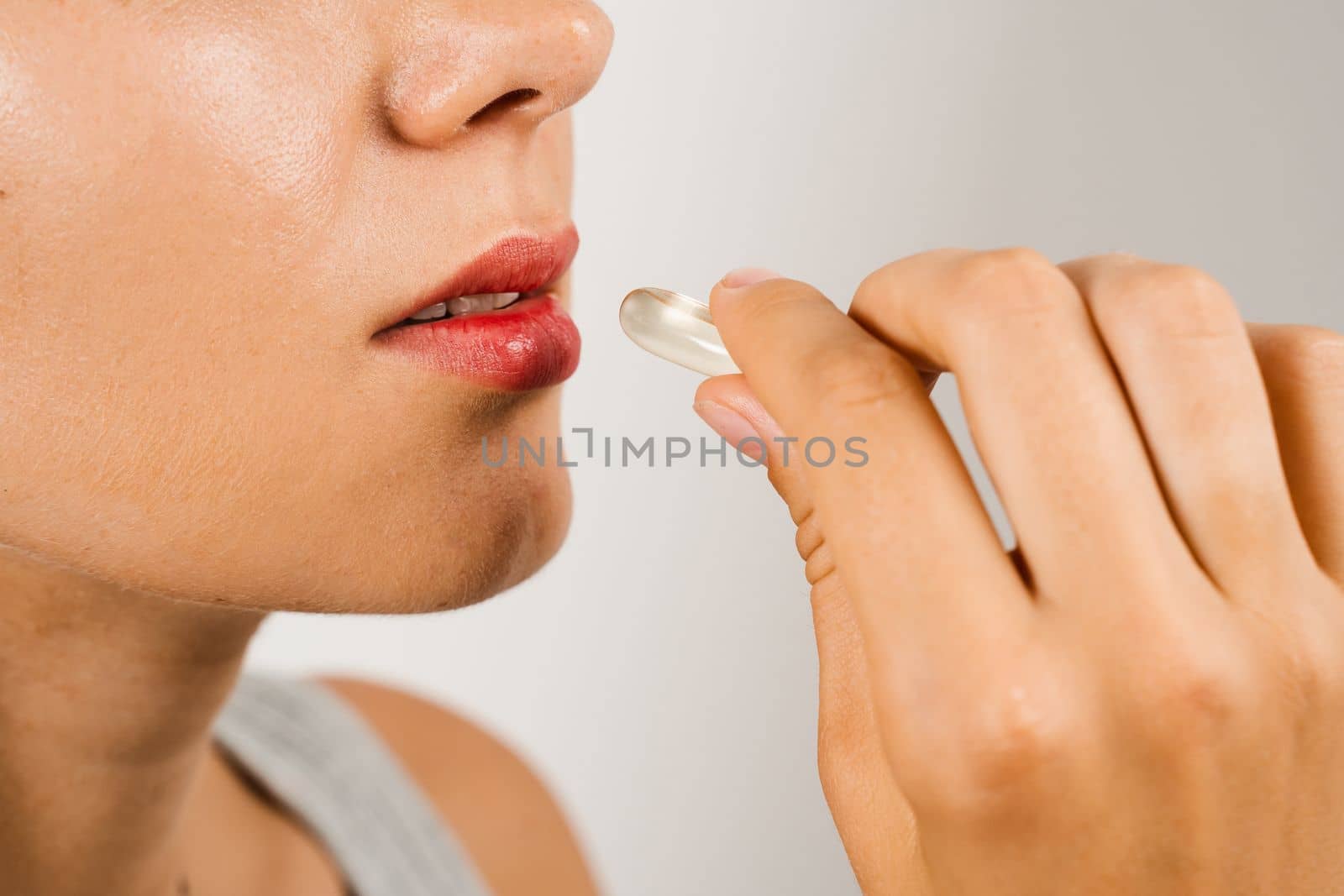 Girl is taking BADS capsule of Omega-3 biologically active dietary supplements close-up. Vitamin D for building and maintaining healthy bones