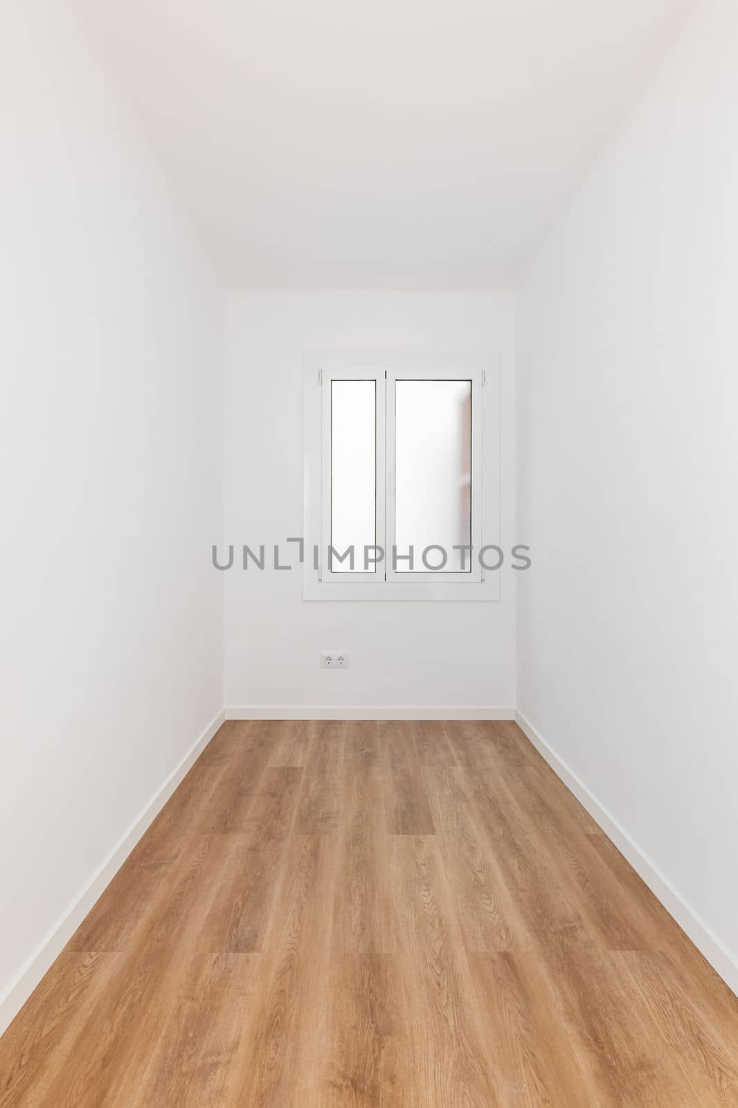 Long narrow rectangular room with white walls and wooden parquet, well lit by daylight from frosted glass window from prying eyes. Several sockets for electrical appliances are built into wall
