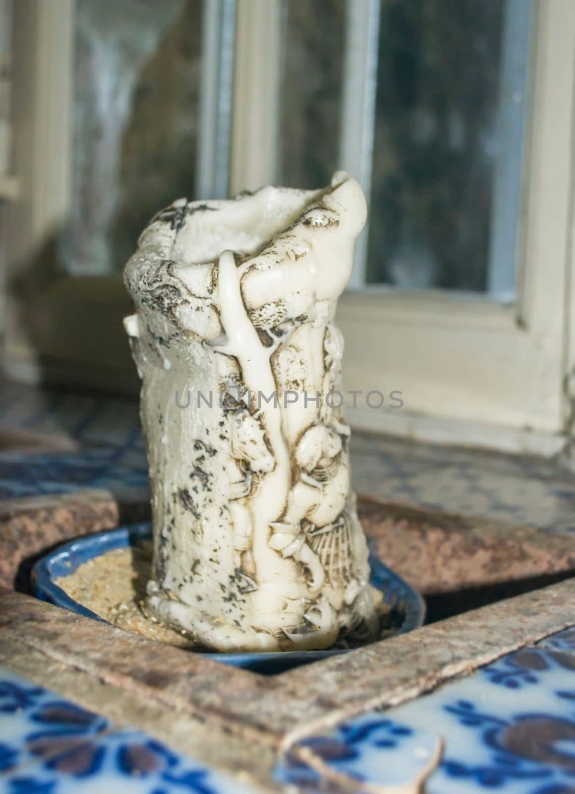 Old vintage carved candle with figures on the window sill