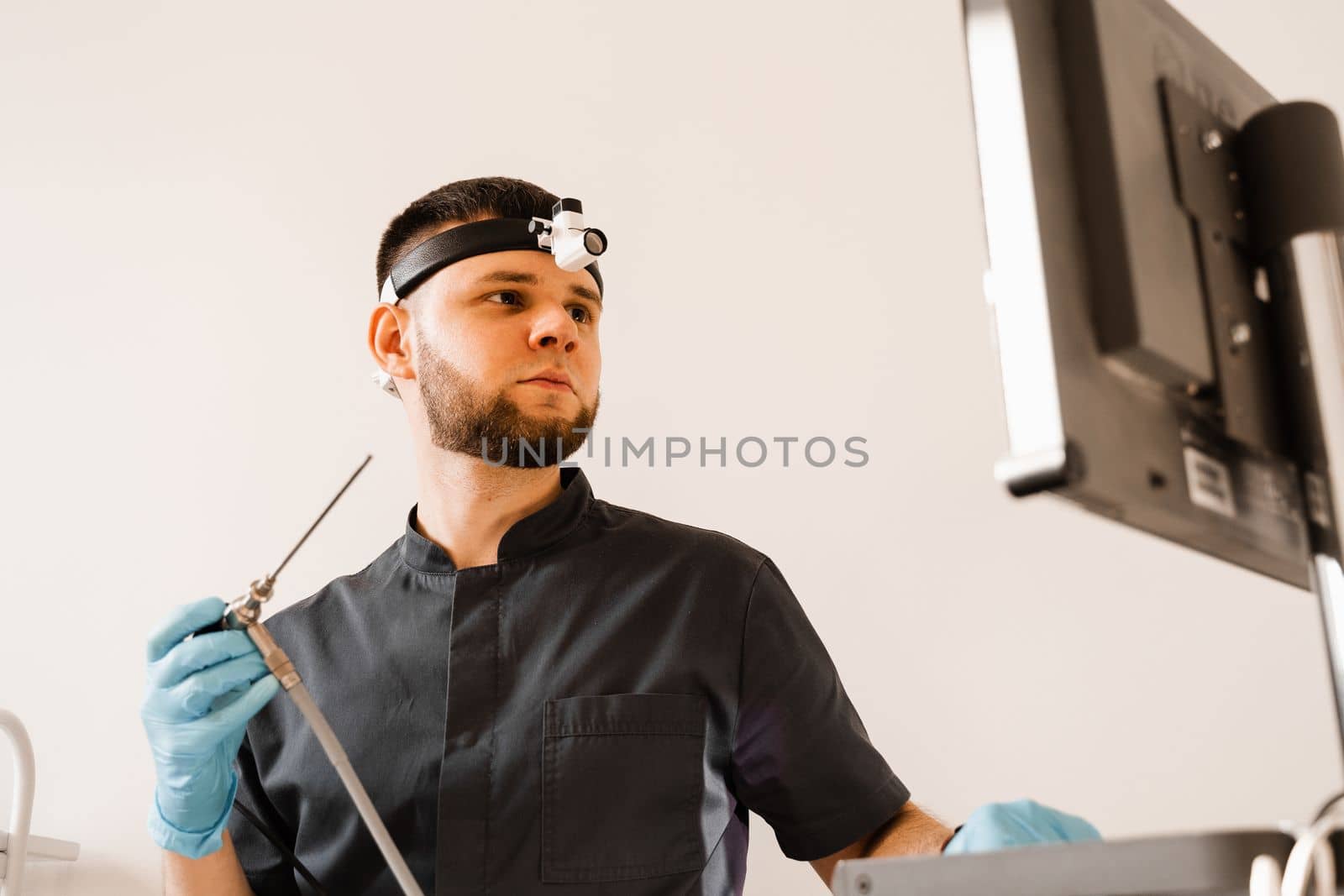 ENT doctor otolaryngologist with endoscope in hands. Prepearing for endoscopy procedure. Doctor with headlight. by Rabizo