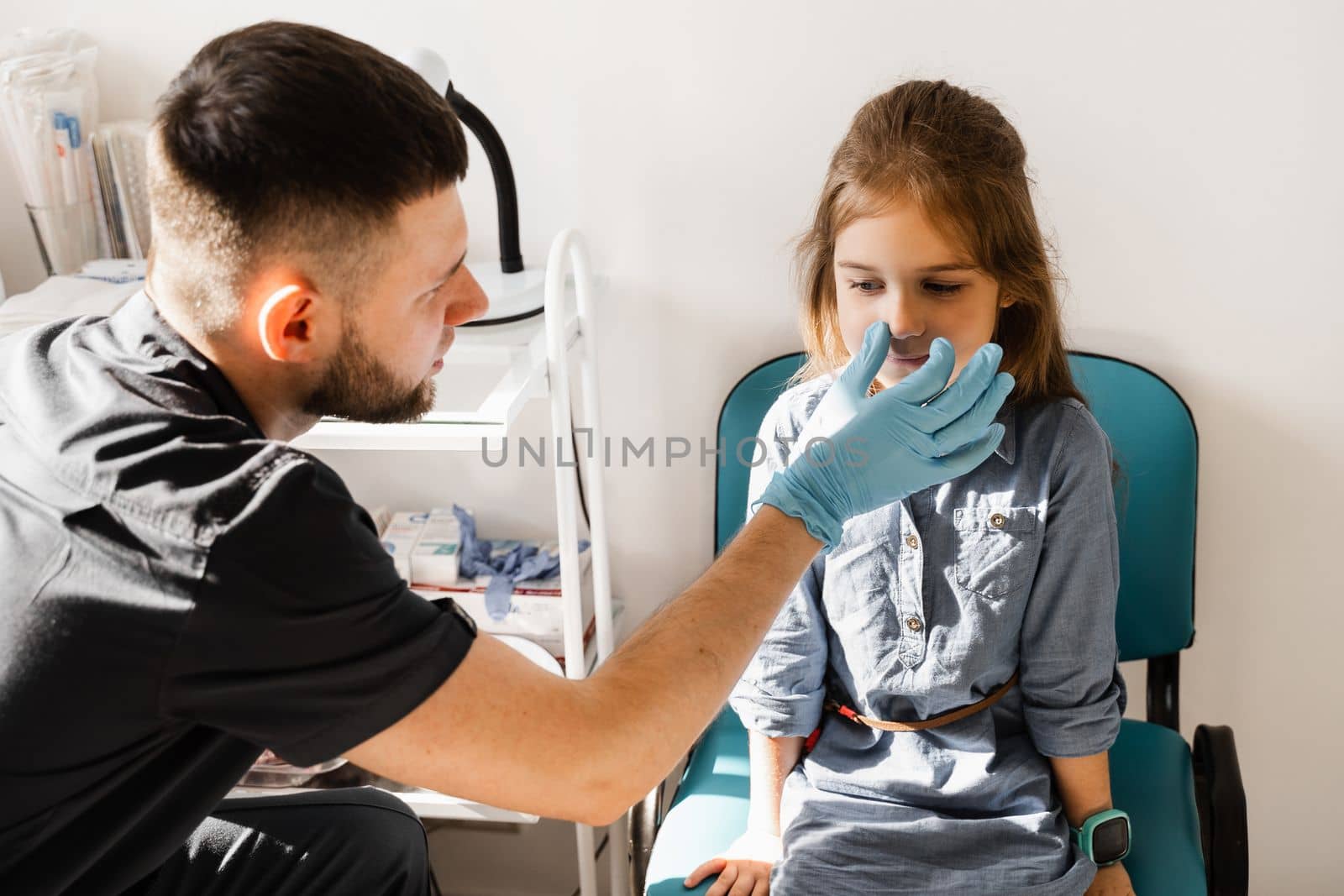 Nose examination of the child. Consultation of kid with a pediatric otolaryngologist in a medical clinic