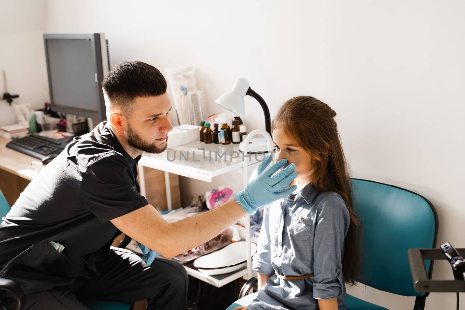 Nose examination of the child. Consultation of kid with a pediatric otolaryngologist in a medical clinic