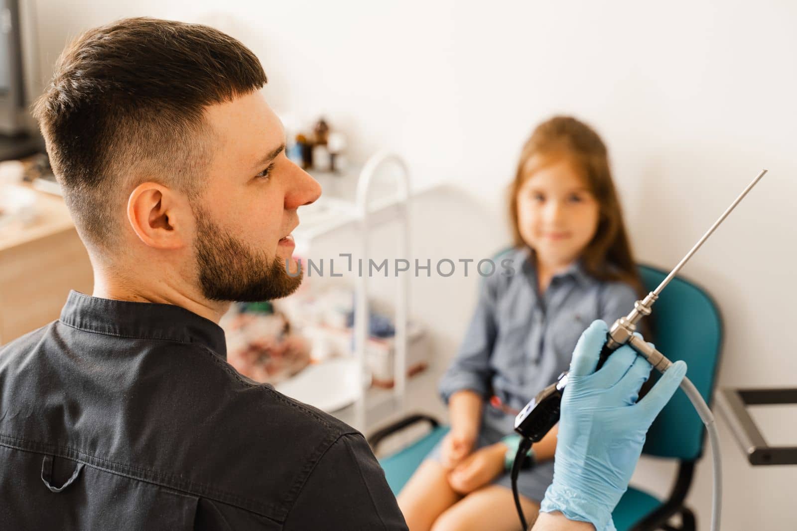 Doctor otolaryngologist with rhinoscope for endoscopy. Child consultation before nasal endoscopy. Examination of child nose and diagnosis of disease. by Rabizo