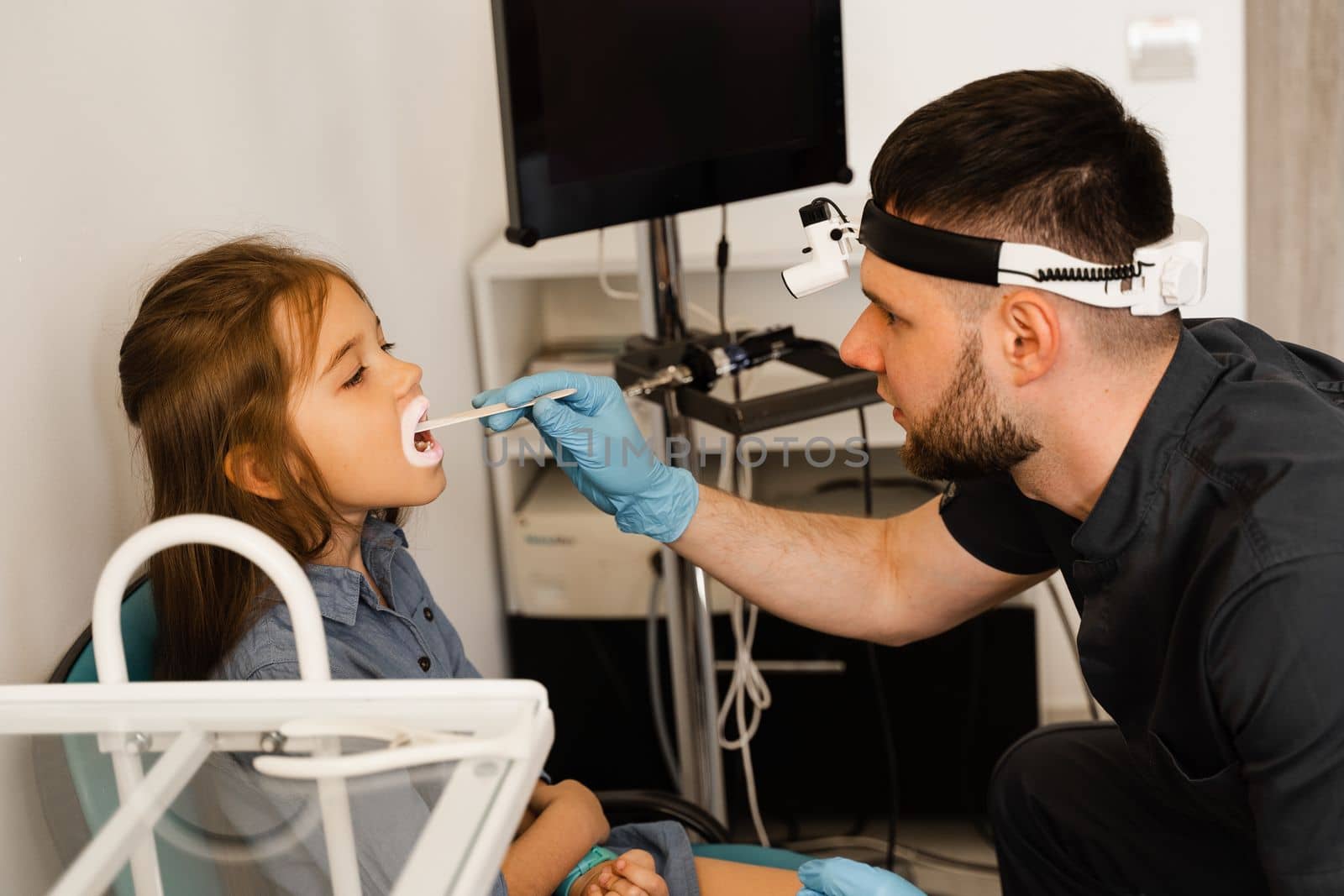 Oropharyngoscopy procedure. Otolaryngologist examines child throat with spatula. Consultation with laryngologist