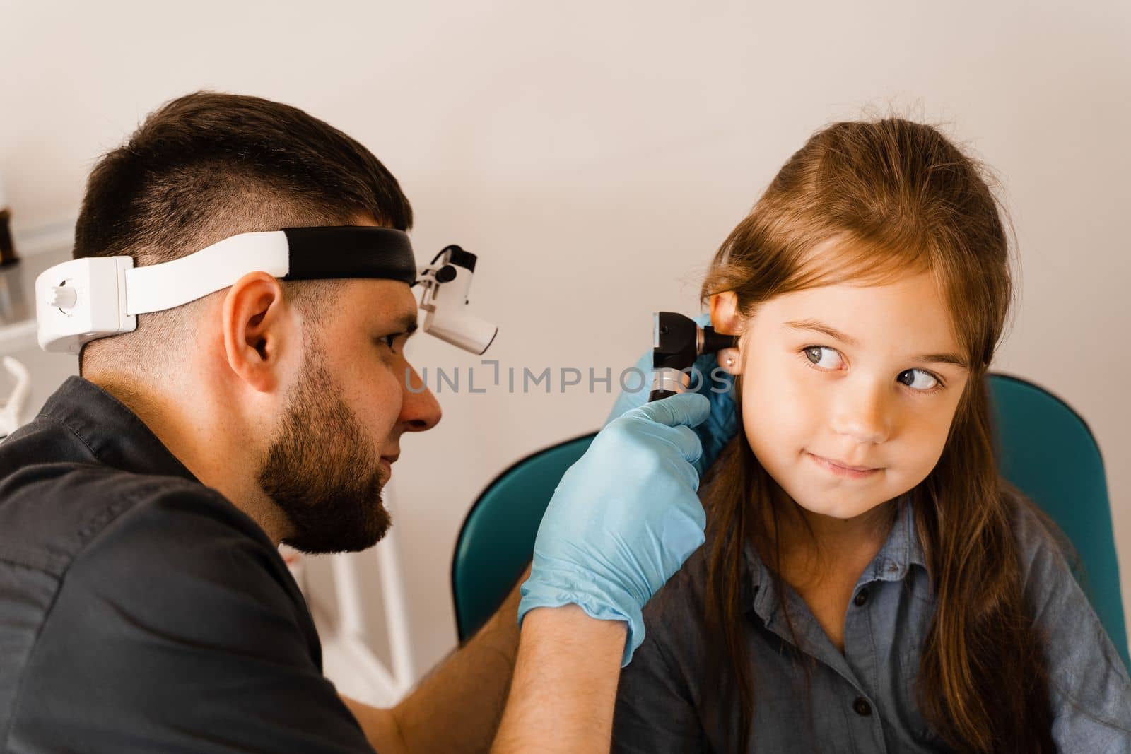 ENT doctor with otoscope. Otoscopy. Pediatrician otolaryngologist looks through otoscope the ears of child. Otoscopy. Treatment ear pain. by Rabizo