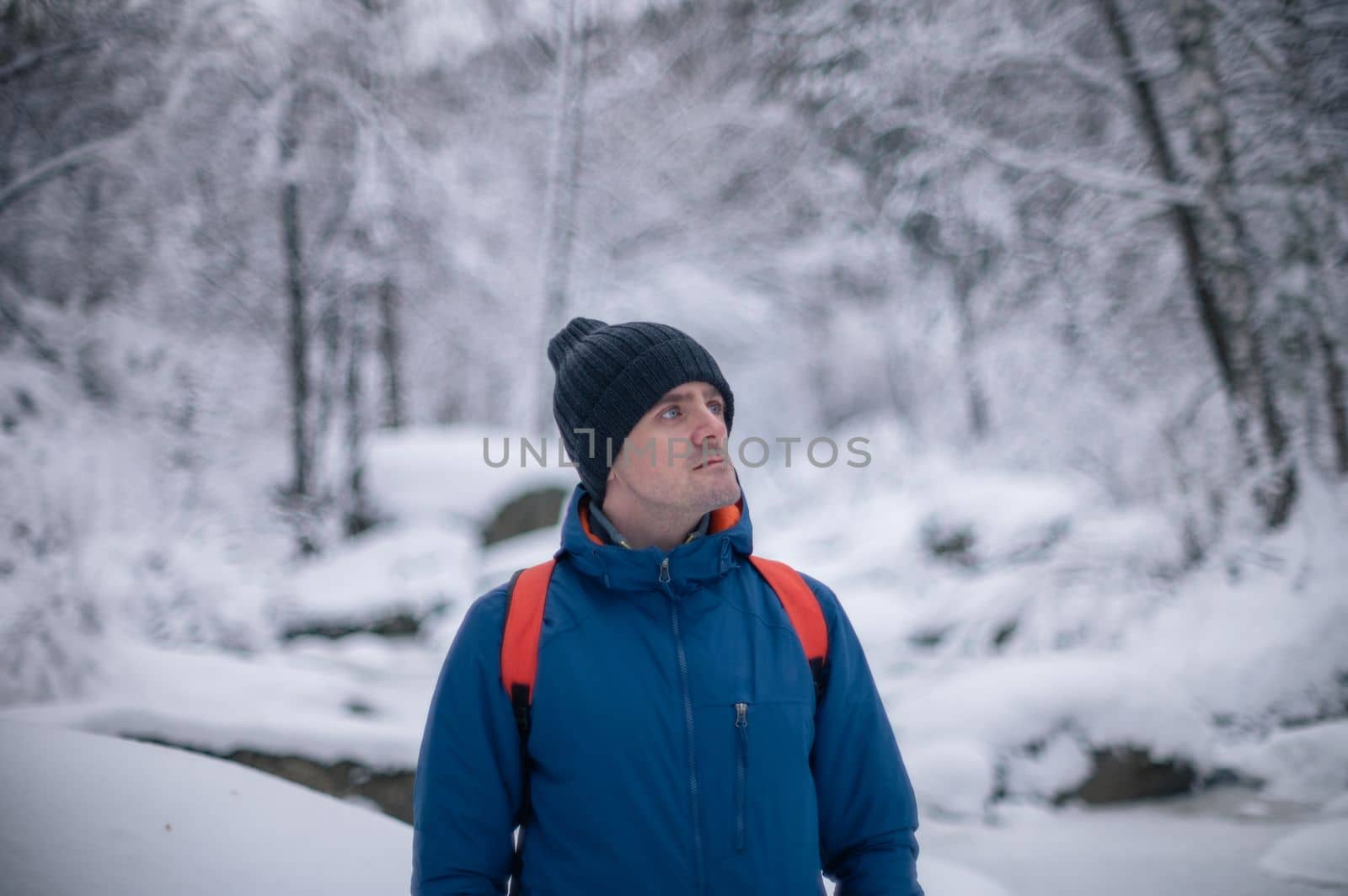 Man in winter jacket walking in snowy winter forest, snowy winter day