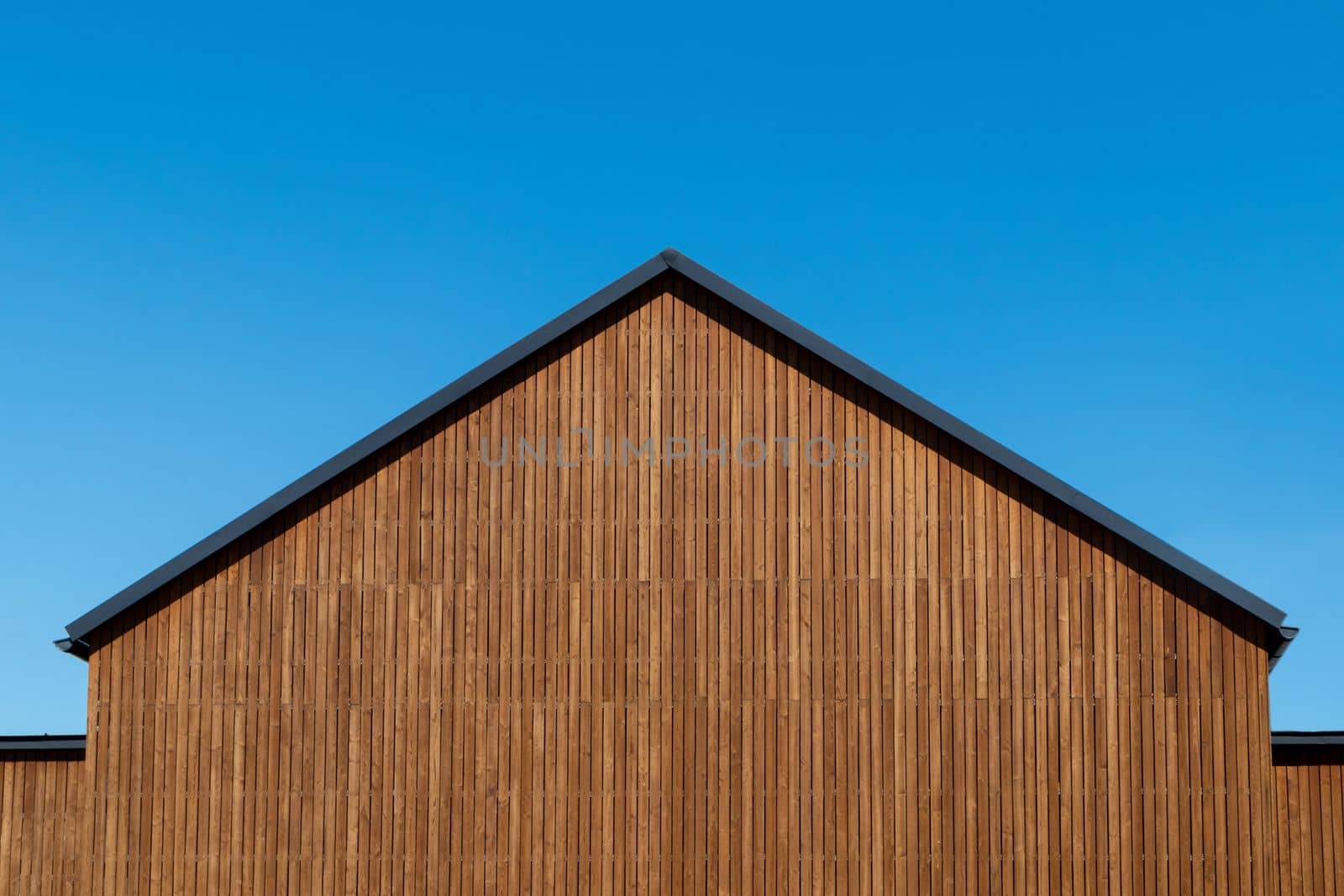 Facade decoration of the roof gable with natural wood plank of a new modern house, copy space.