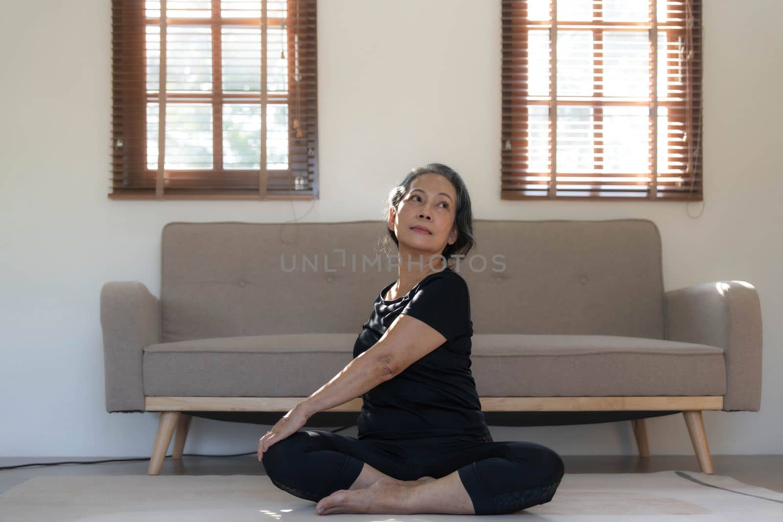 Healthy and happy 60s retired Asian woman in workout clothes practicing yoga in her living room...