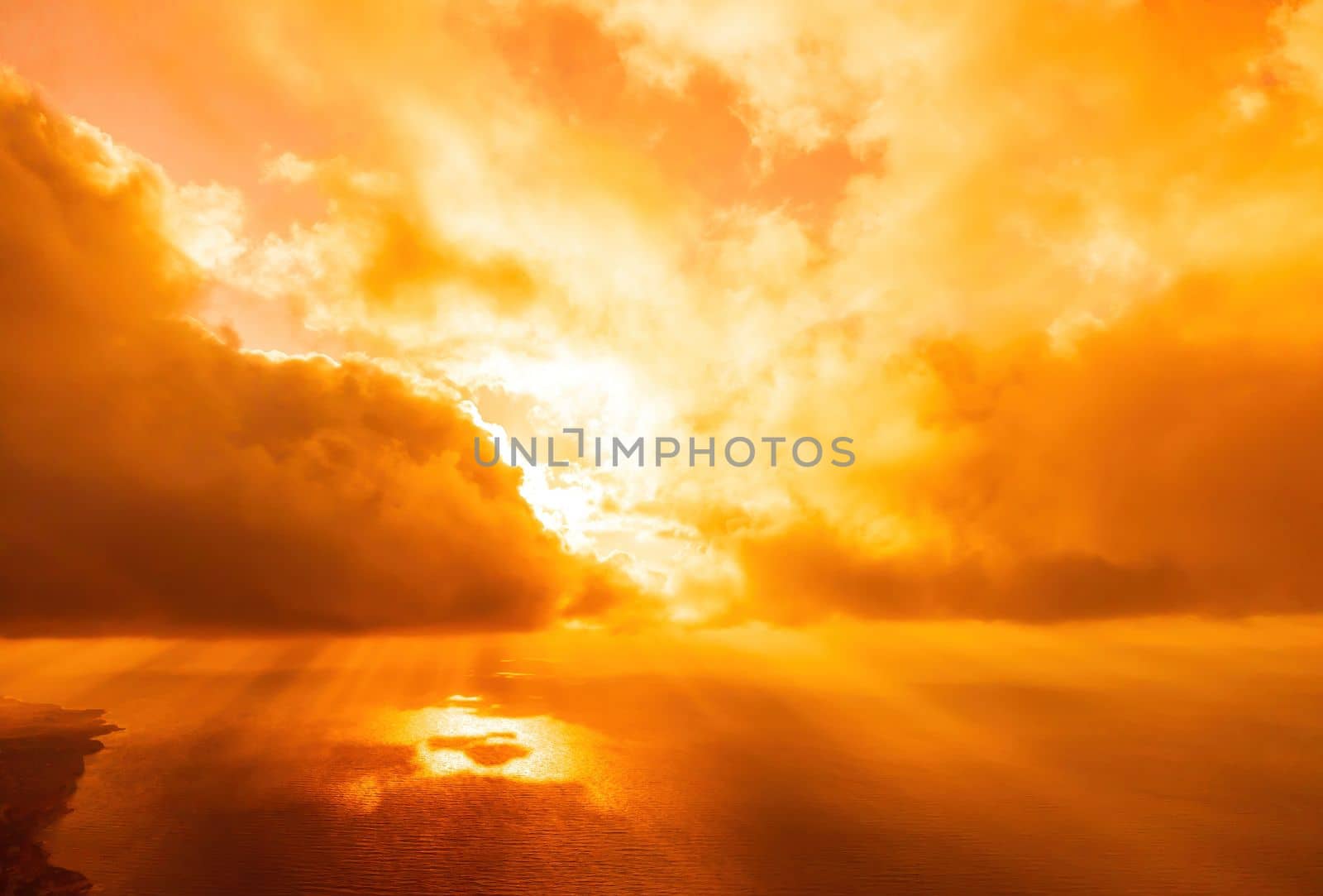 Aerial view red burning sunset over the sea with rocky volcanic cliff. Abstract nature summer sunset ocean sea background. Small waves on golden warm water surface Evening. Horizon. Nobody. No people. by panophotograph