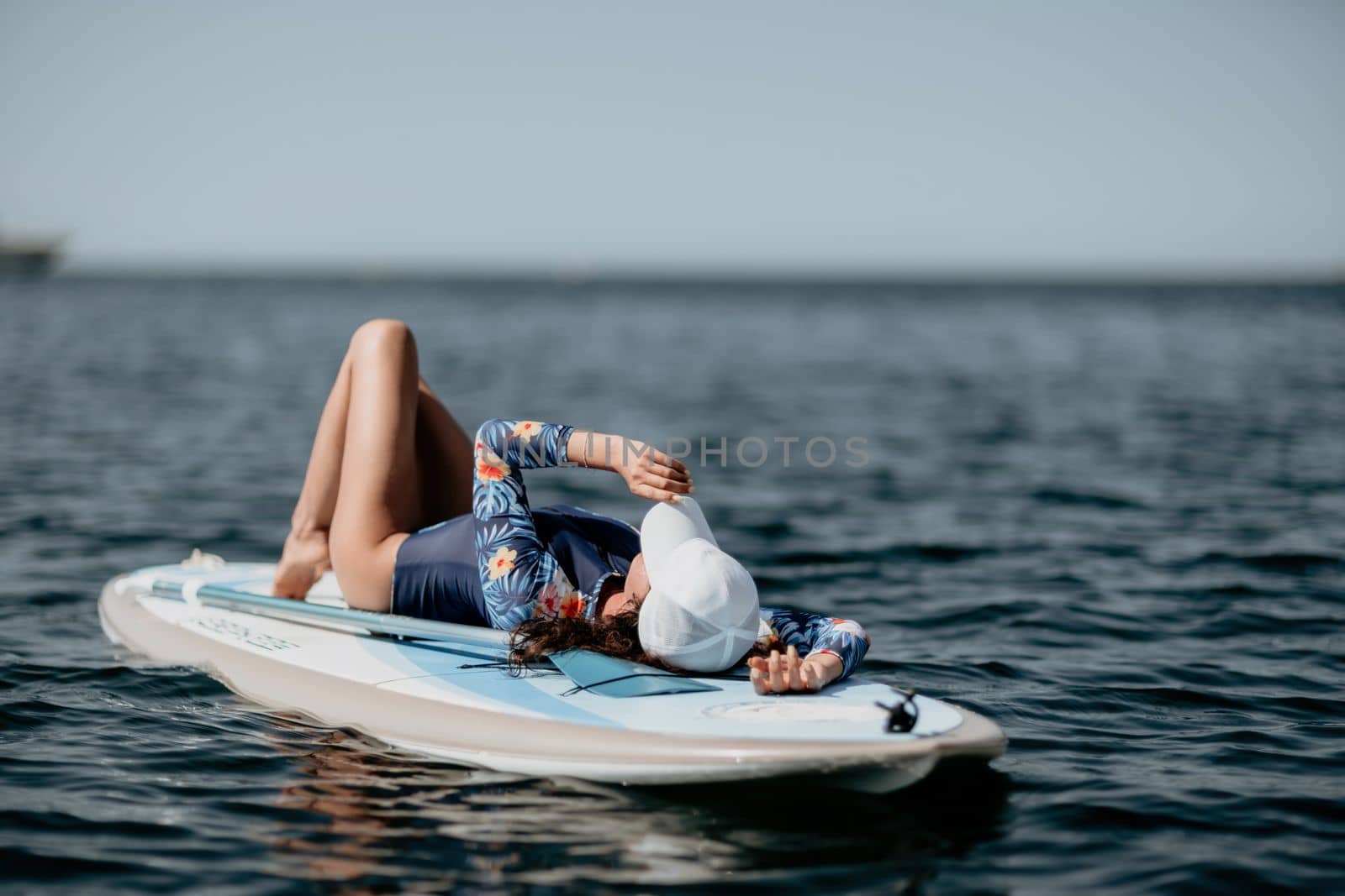 Woman sup yoga. Middle age sporty woman practising yoga pilates on paddle sup surfboard. Female stretching doing workout on sea water. Modern individual hipster outdoor summer sport activity