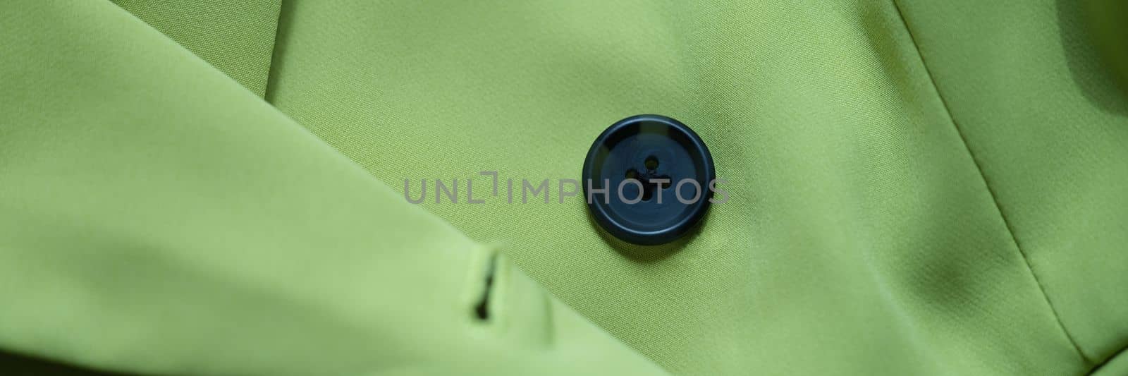 Closeup of green jacket with black button. Selection of accessories and buttons for clothing concept