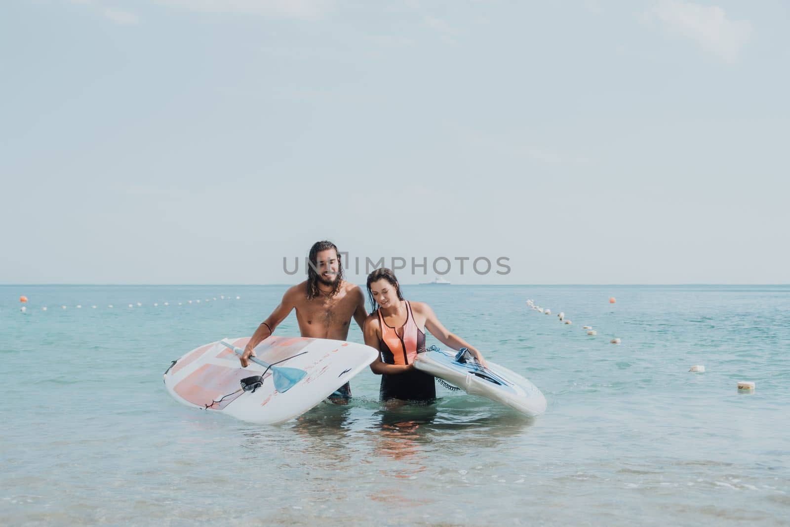 Woman man sea sup. Close up portrait of beautiful young caucasian woman with black hair and freckles looking at camera and smiling. Cute woman portrait in a pink bikini posing on sup board in the sea
