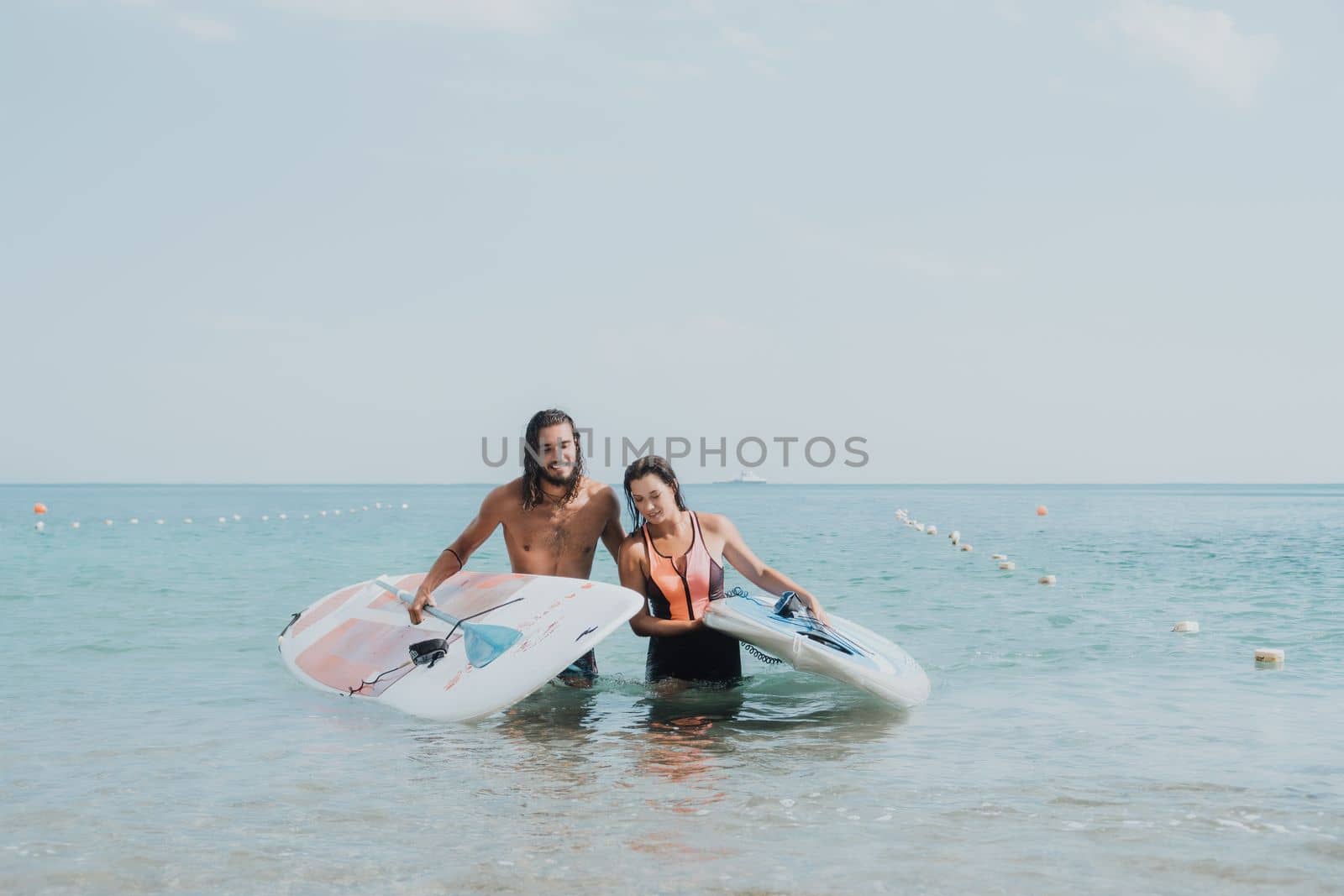 Woman man sea sup. Close up portrait of beautiful young caucasian woman with black hair and freckles looking at camera and smiling. Cute woman portrait in a pink bikini posing on sup board in the sea. by panophotograph