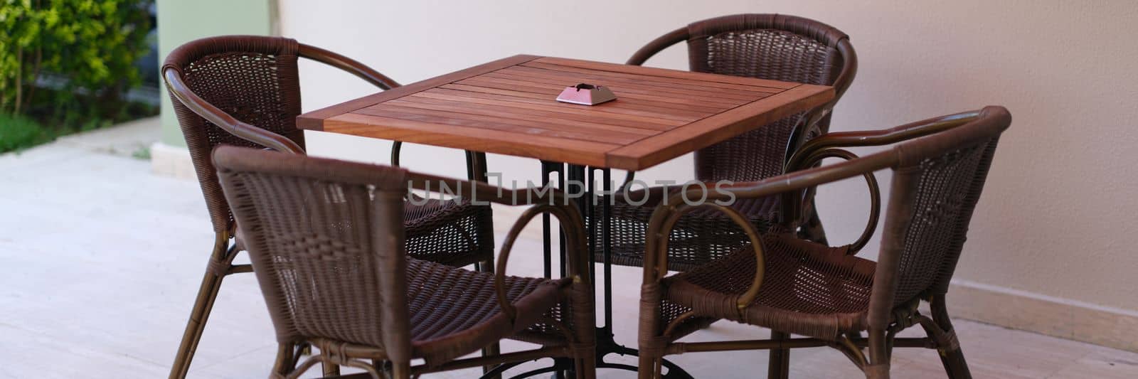 Summer wooden table and wicker chairs on veranda. Summer outdoor furniture concept