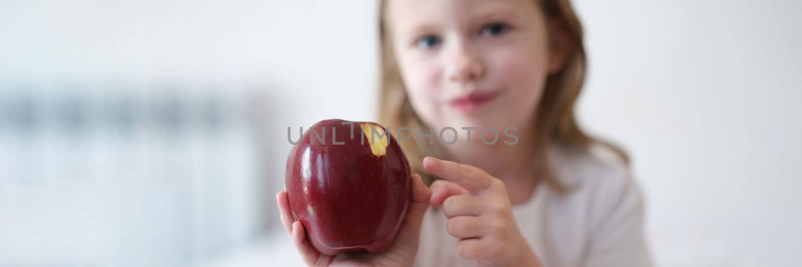 Girl child bites and eats big red apple by kuprevich